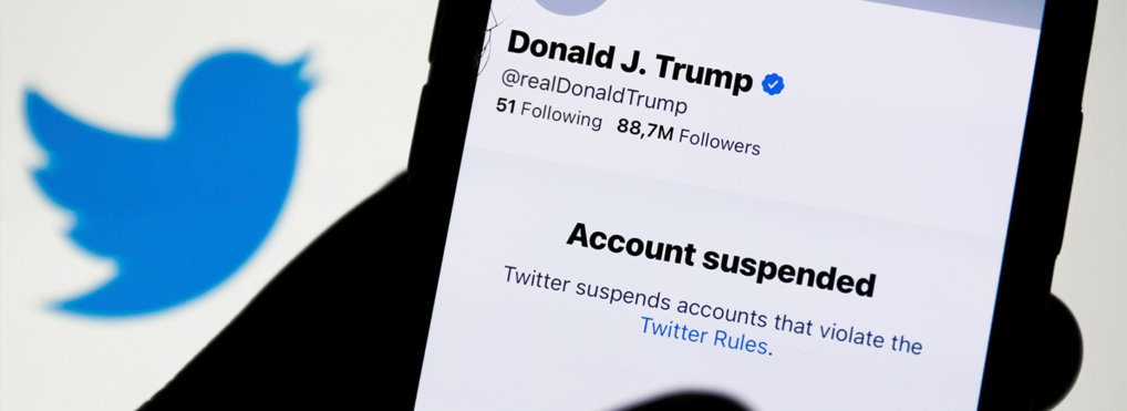 Donald Trump's Twitter account displayed on a phone screen and Twitter logo in the background