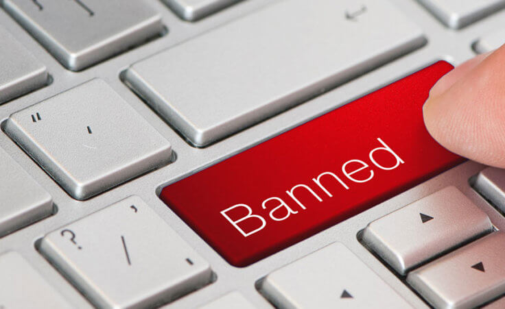 A finger presses a keyboard button labeled "Banned"