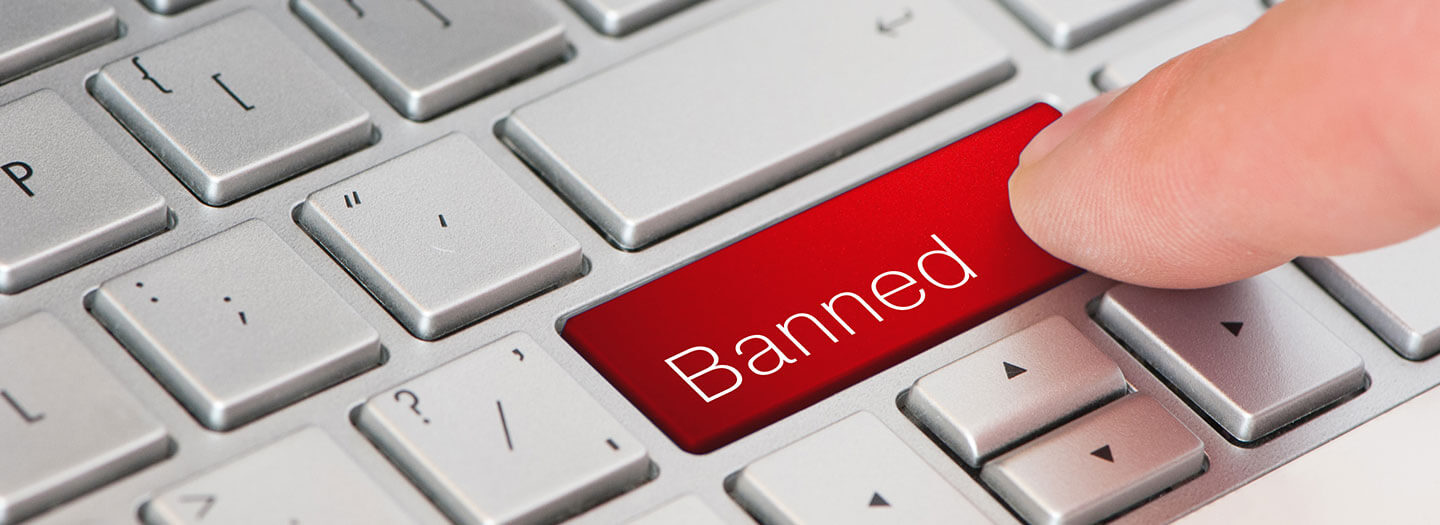 A finger presses a keyboard button labeled "Banned"