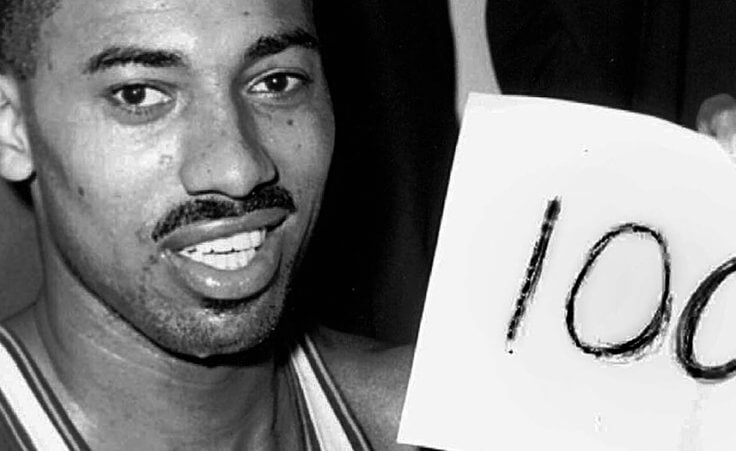 Wilt Chamberlain holds a sign reading "100"