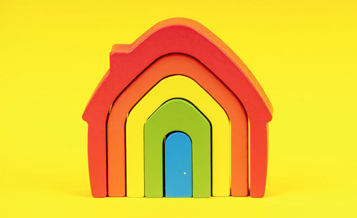 Wooden rainbow flag toy house on yellow background