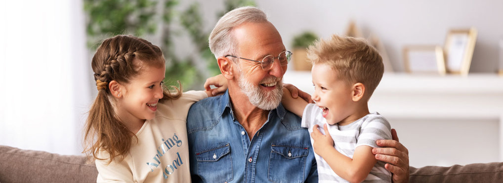 A grandfather hugs his grandson and granddaughter