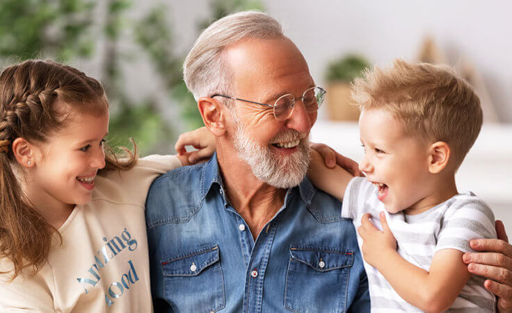 A grandfather hugs his grandson and granddaughter