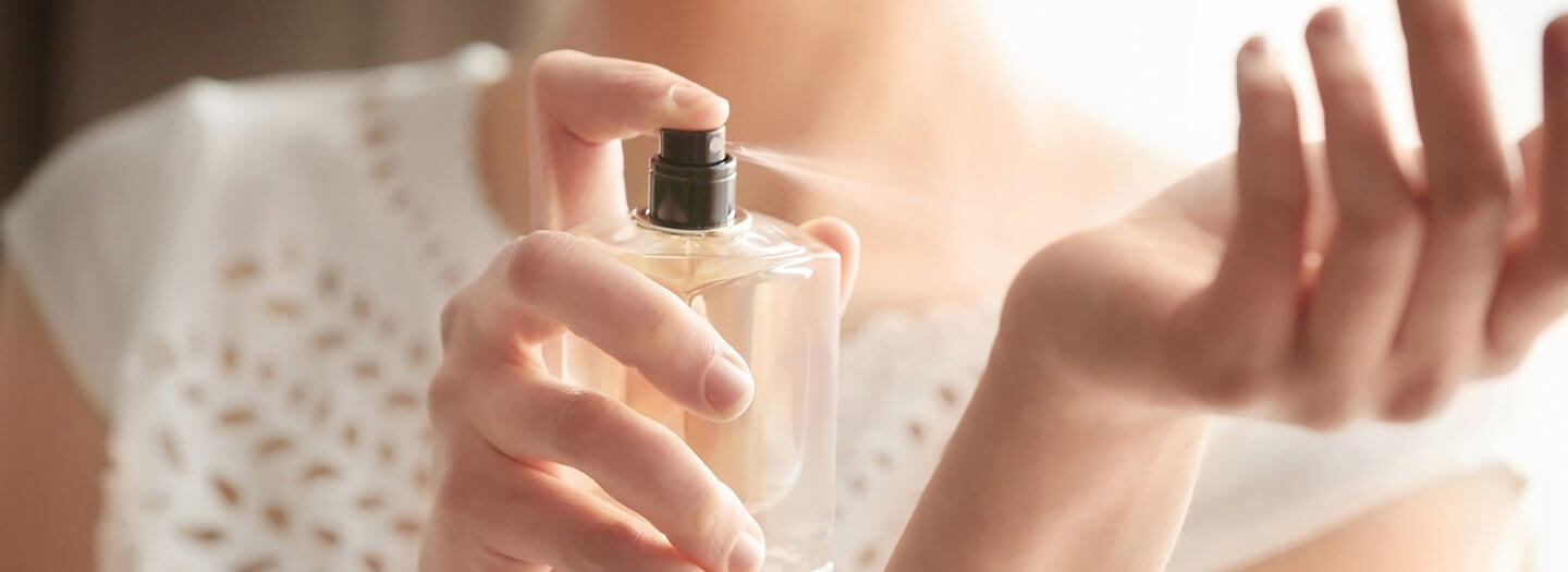 A woman spritzes her wrist with perfume