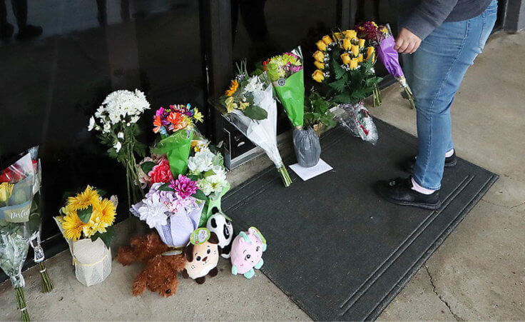 FILE - In this March 17, 2021, file photo, Jessica Lang pauses and places her hand on the door in a moment of grief after dropping off flowers with her daughter Summer at Youngs Asian Massage parlor where four people were killed in Acworth, Ga. (Curtis Compton/Atlanta Journal-Constitution via AP, File)