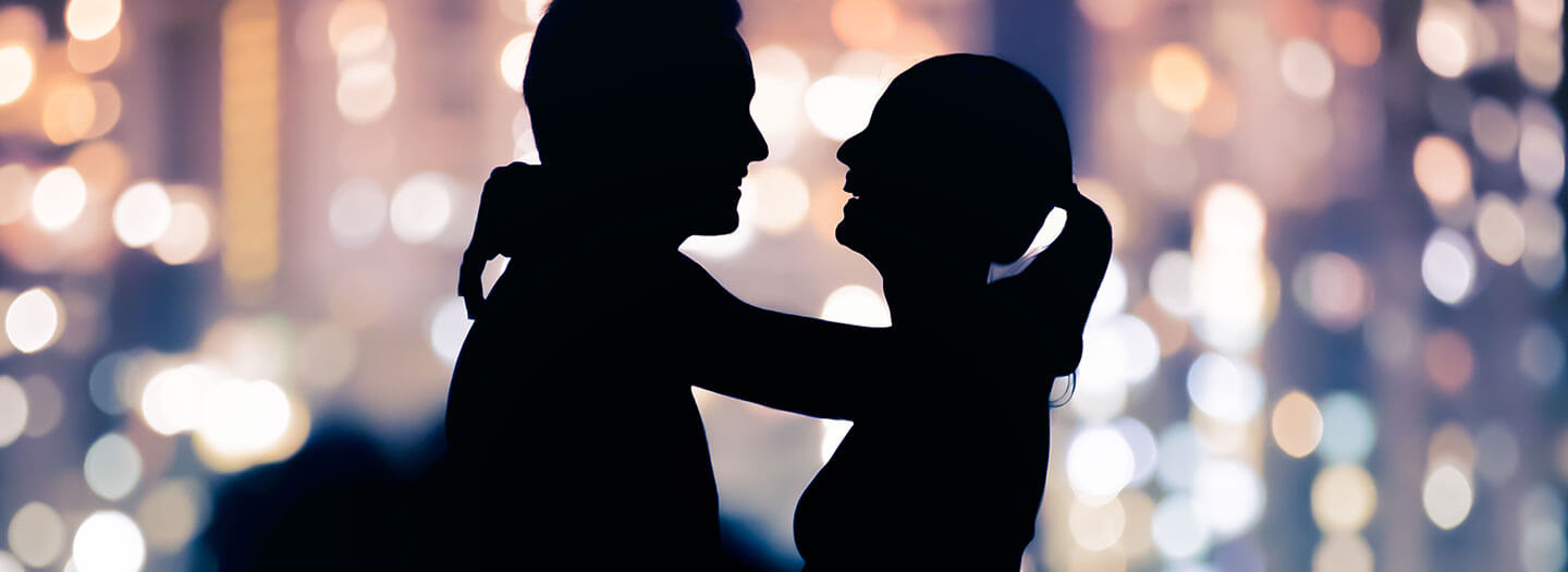 A woman lovingly drapes her arms around a man's neck