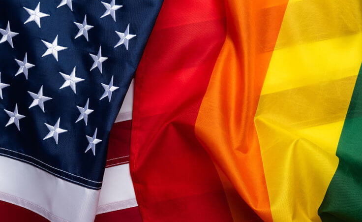 A rainbow flag draped over an American flag