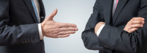 One businessman attempts to shake another businessman's hand