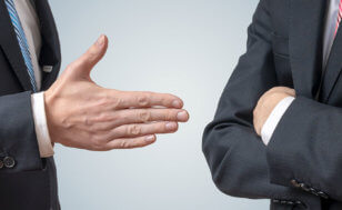 One businessman attempts to shake another businessman's hand