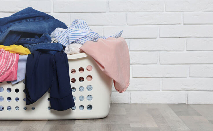 A laundry basket overflows with dirty laundry
