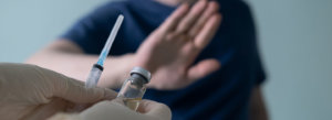 A man in a mask waves off receiving a vaccination