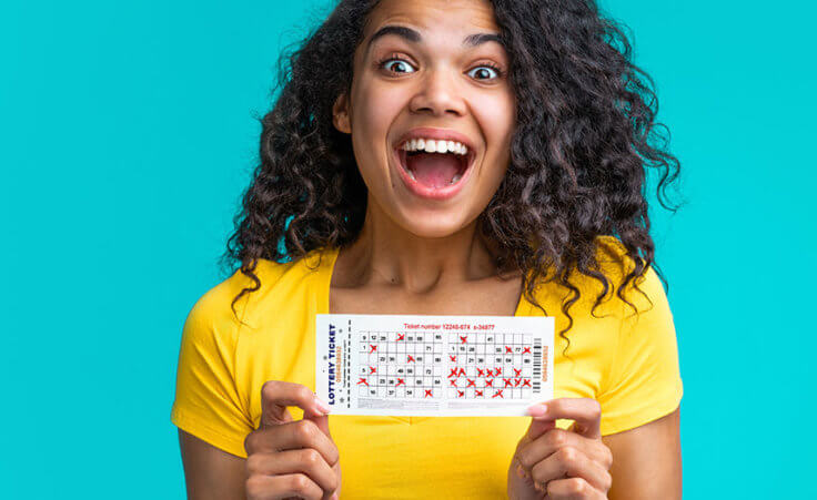 An excited woman holds up a winning lottery ticket