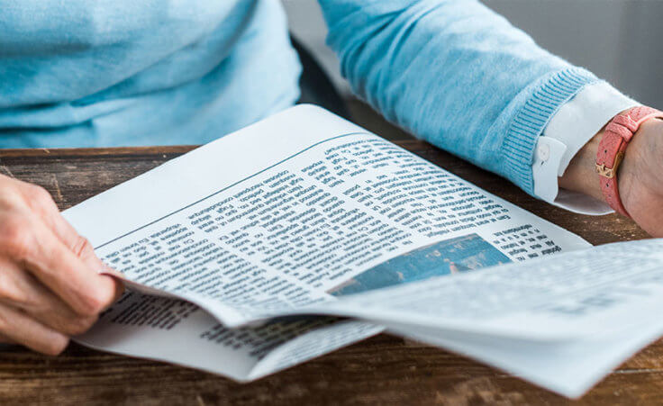 A man reads the front page of a newspaper on his desk