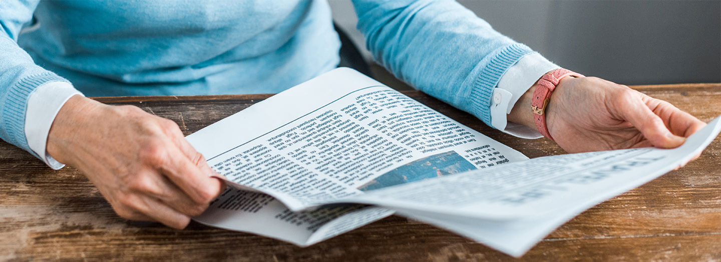 A man reads the front page of a newspaper on his desk