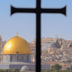 A cross sits in the foreground against the Dome of the Rock mosque in Jerusalem