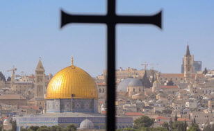 A cross sits in the foreground against the Dome of the Rock mosque in Jerusalem