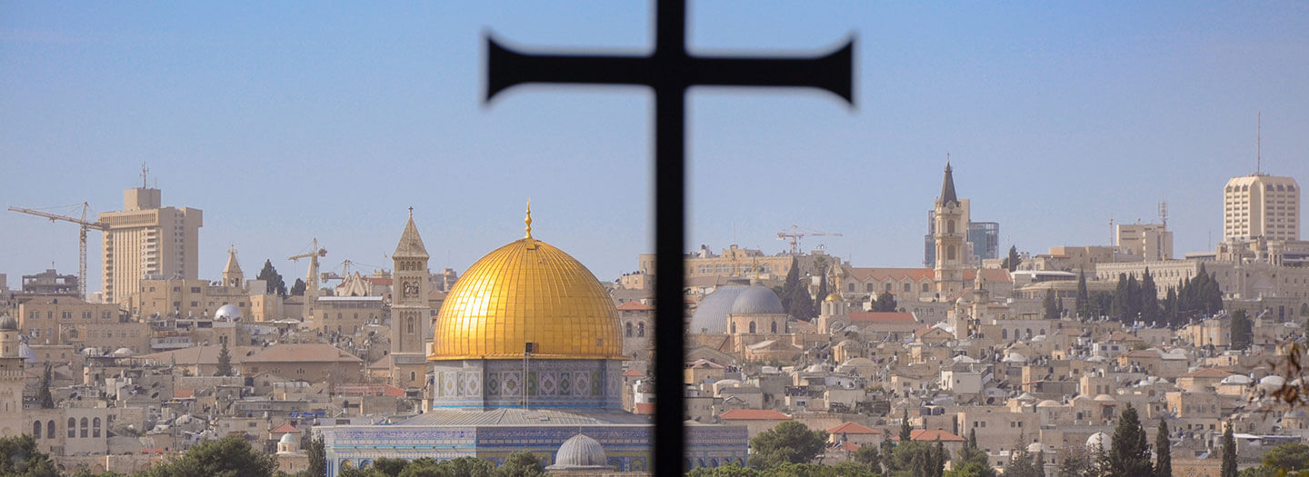 A cross sits in the foreground against the Dome of the Rock mosque in Jerusalem