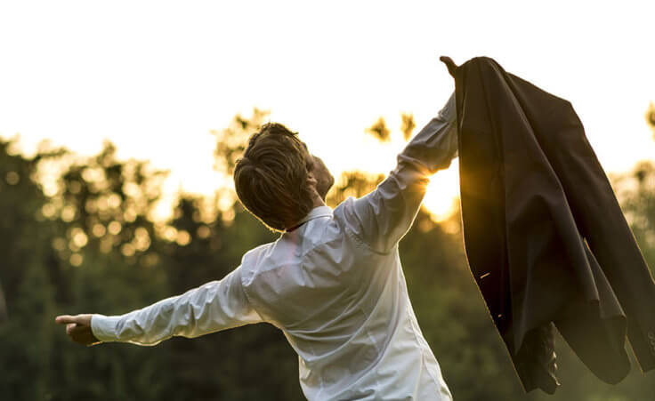 Young businessman holding his jacket with arms spread widely in a forest