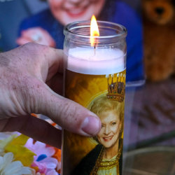 A fan places a candle at the Hollywood Walk of Fame star of the late actress Betty White, Friday, Dec. 31, 2021, in Los Angeles. (AP Photo/Ringo H.W. Chiu)