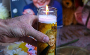 A fan places a candle at the Hollywood Walk of Fame star of the late actress Betty White, Friday, Dec. 31, 2021, in Los Angeles. (AP Photo/Ringo H.W. Chiu)