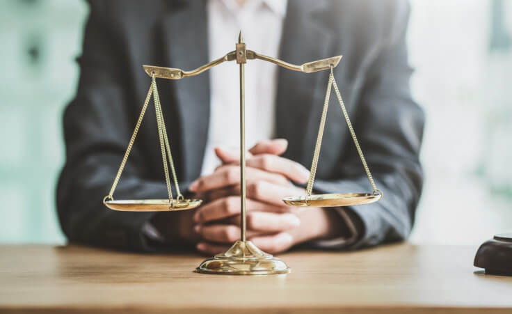 Close up golden scales with blurry lawyer as background. By Phushutter/stock.adobe.com