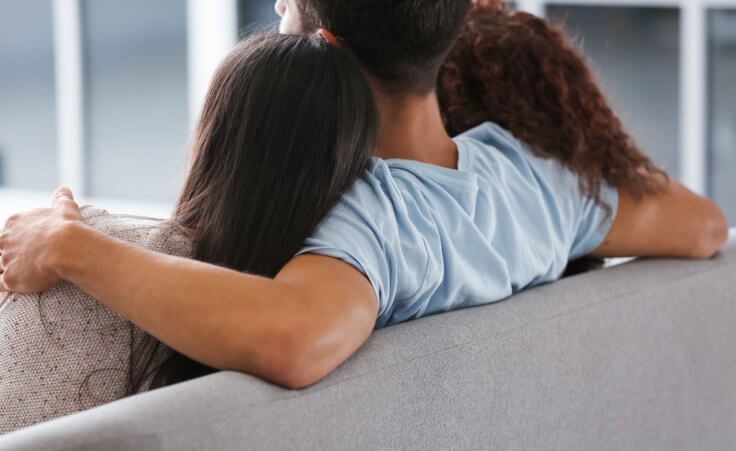 A man sits on a couch with a woman on either side of him