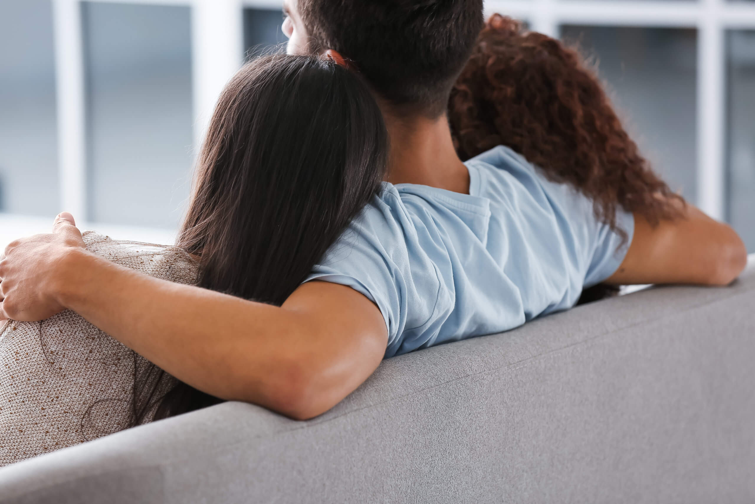 A man sits on a couch with a woman on either side of him