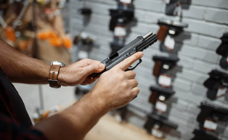 Man choosing new handgun in gun shop. What does the Bible say about gun control?