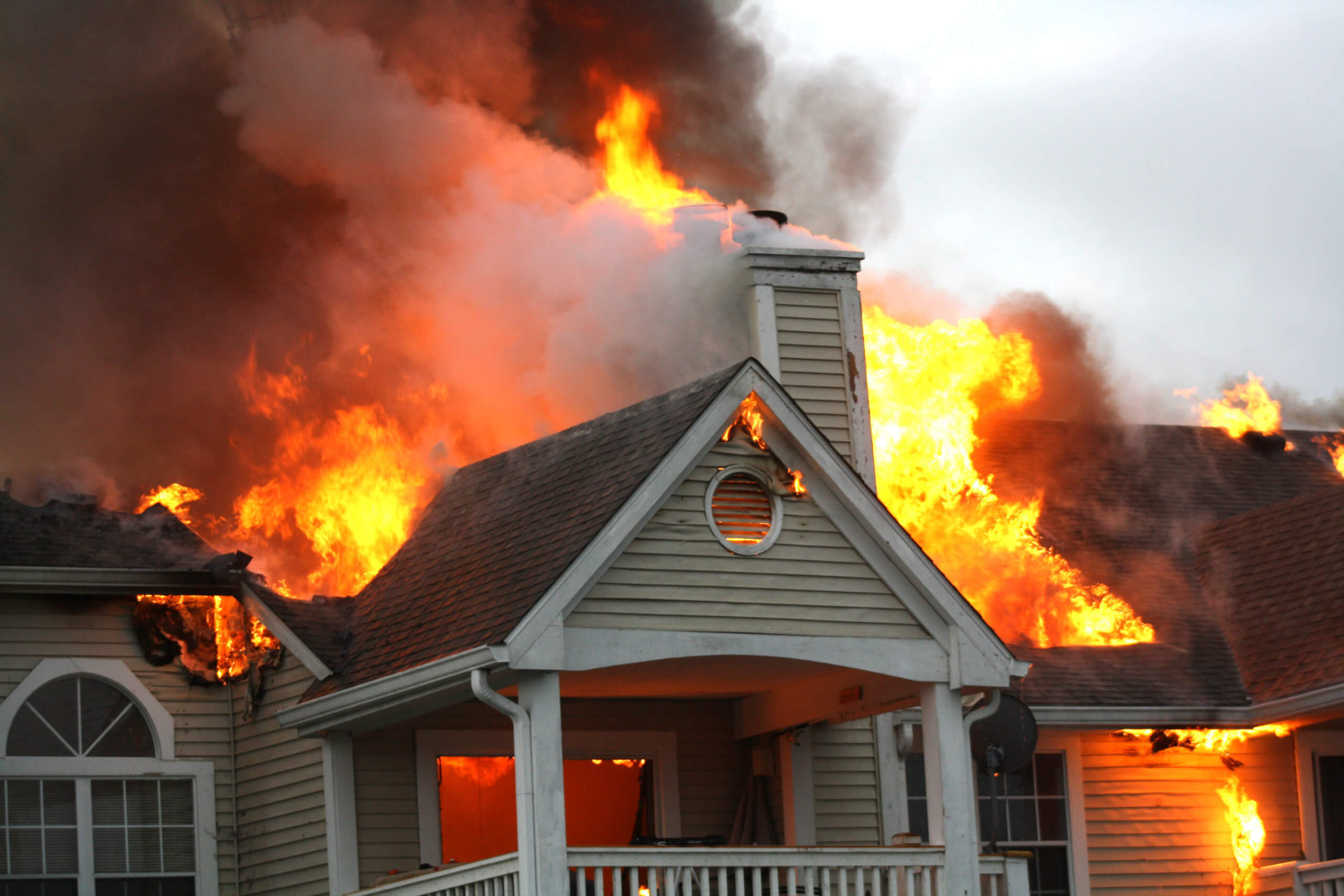 Stock photo: Flames spew at the top of a beige house on fire. © Sue/stock.adobe.com