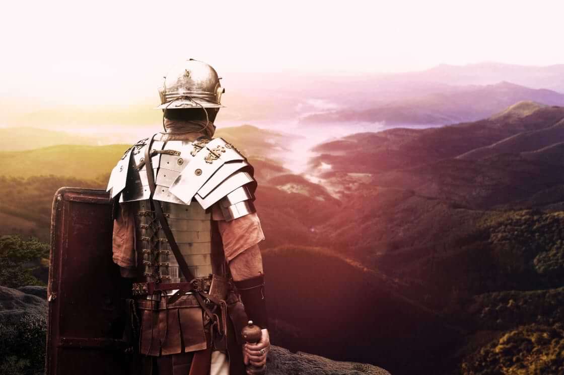 An ancient Roman legion soldier peers over a valley. © serpeblu/stock.adobe.com