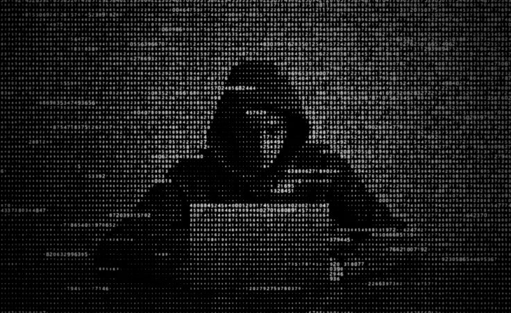 A hacker in a hoodie sits behind a laptop. © Oleksii /stock.adobe.com