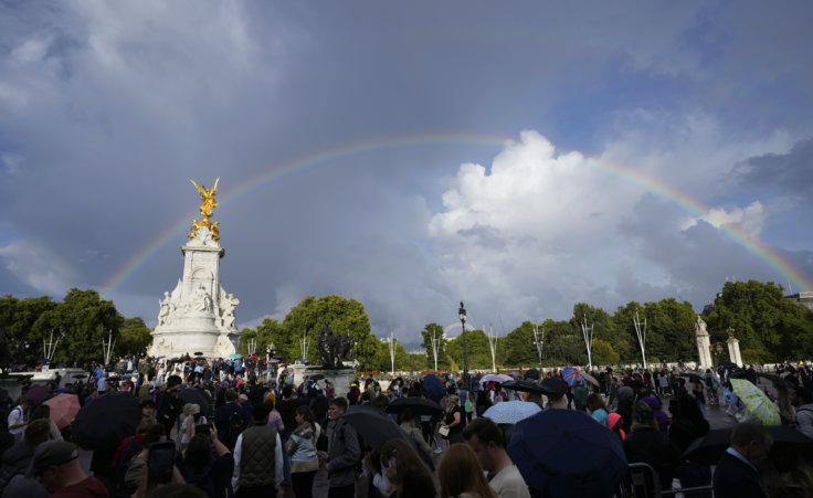 Shortly before the announcement of Queen Elizabeth II's death, people gather outside Buckingham Palace in London as a double rainbow appears in the sky, Thursday, Sept. 8, 2022. (AP Photo/Frank Augstein)