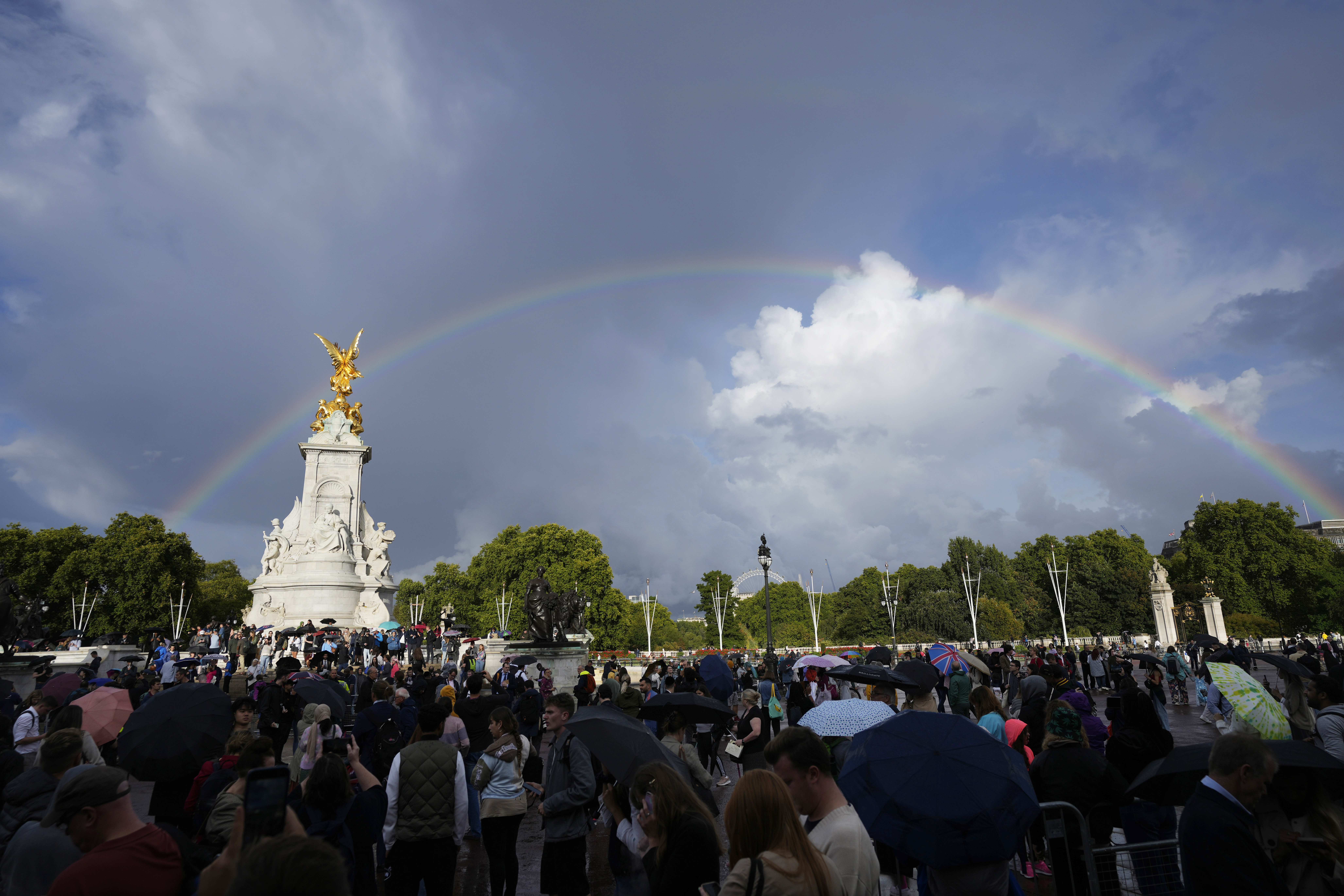 Shortly before the announcement of Queen Elizabeth II's death, people gather outside Buckingham Palace in London as a double rainbow appears in the sky, Thursday, Sept. 8, 2022. (AP Photo/Frank Augstein)