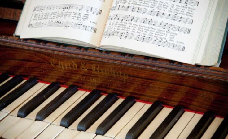 An open hymnbook sits atop a piano. © Don R. Cline /stock.adobe.com