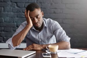 Man with head in his hand, tired with coffee