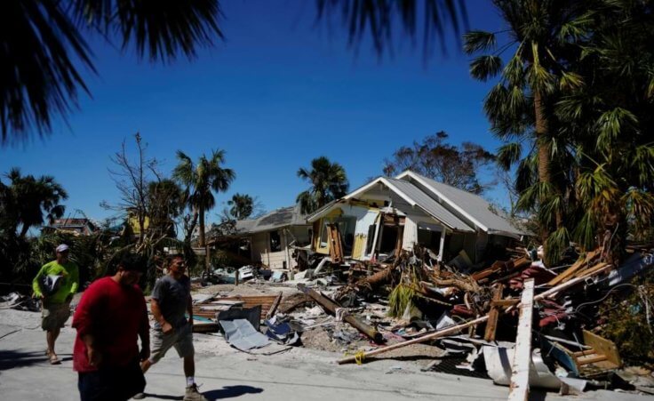 Men walk past destroyed homes and debris as they walk to survey damage to other properties, two days after the passage of Hurricane Ian, in Fort Myers Beach, Fla., Friday, Sept. 30, 2022. (AP Photo/Rebecca Blackwell)