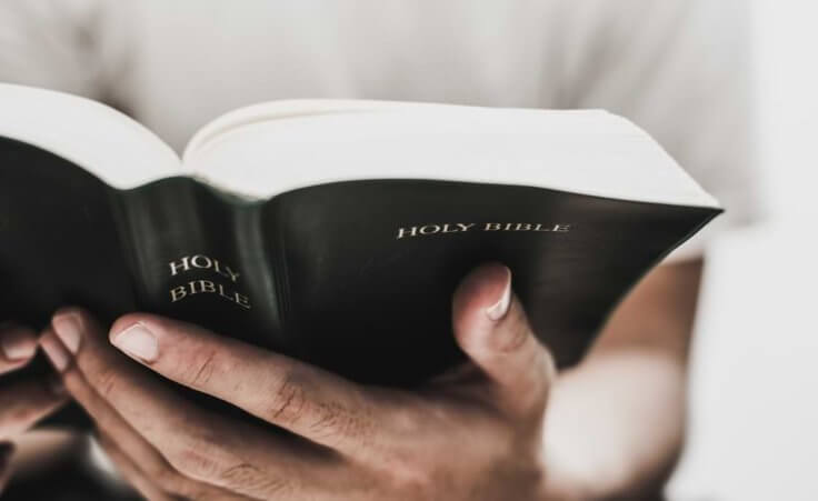 A man holds an open Bible in his hands