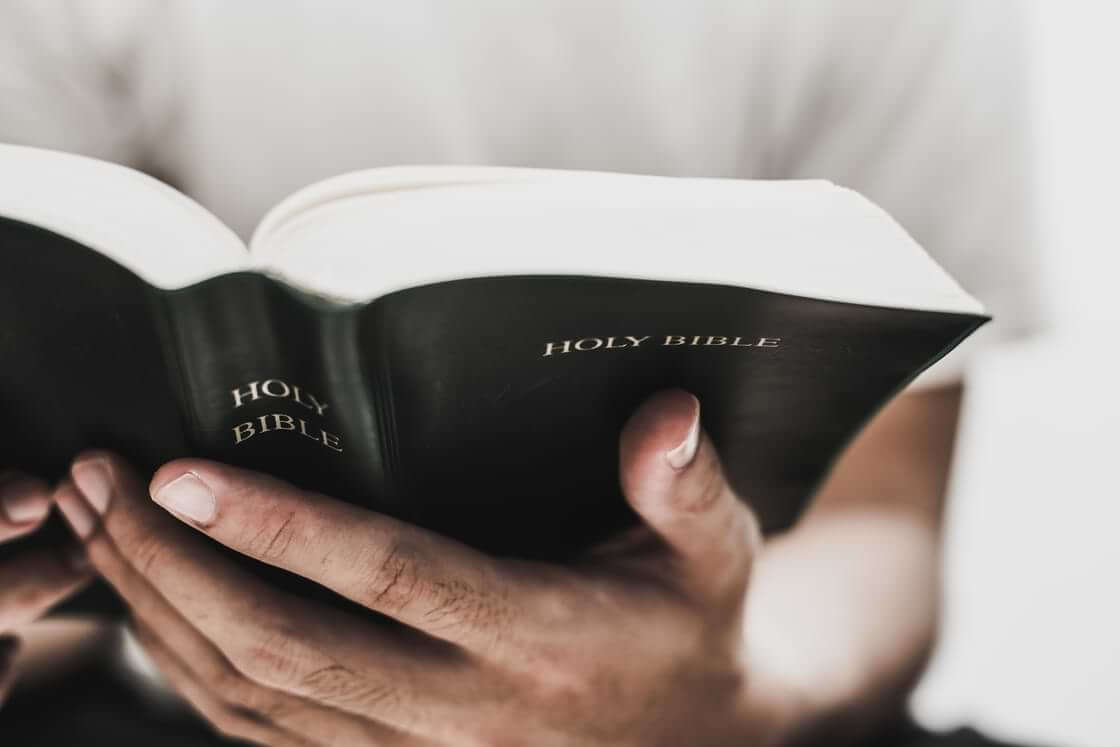 A man holds an open Bible in his hands