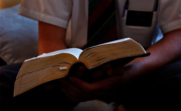 A member of the Church of Jesus Christ of Latter-day Saints sits with an open Bible in his hands.