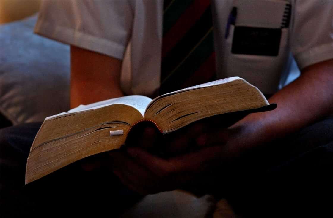 A member of the Church of Jesus Christ of Latter-day Saints sits with an open Bible in his hands.