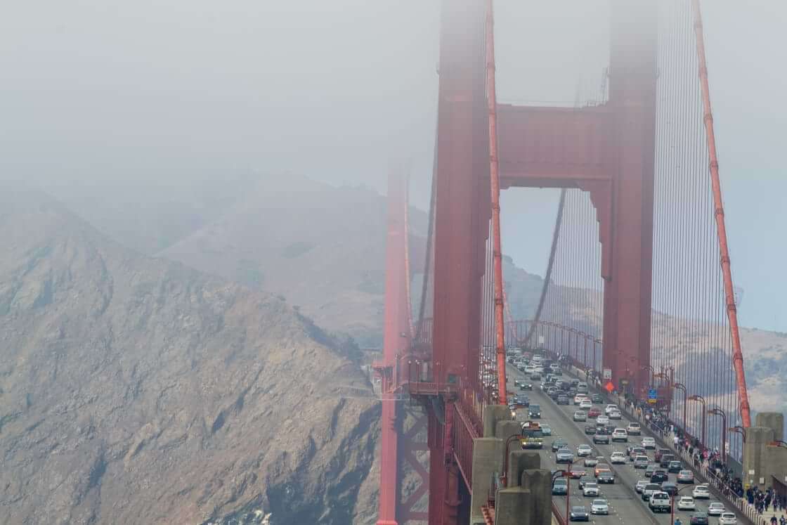 On a foggy morning in San Francisco, cars and pedestrians cross the Golden Gate Bridge.