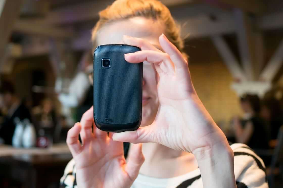 A woman takes a photo with her cell phone.