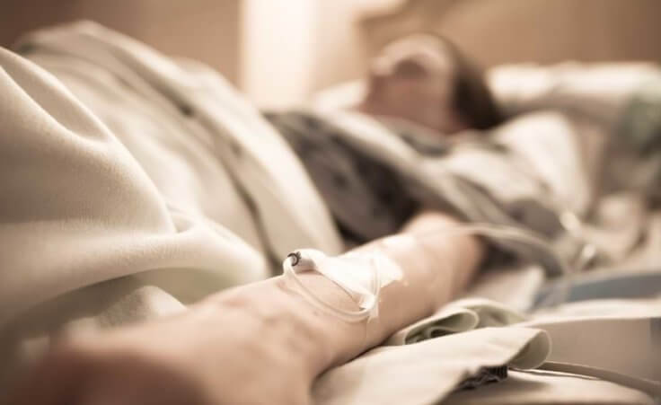 Unrecognizable sick woman lying in hospital bed.