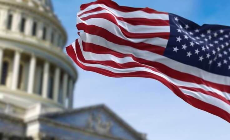 An American flag waves in front of the Capitol building