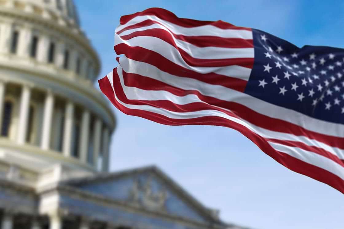 An American flag waves in front of the Capitol building