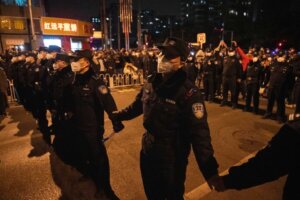 Chinese policemen form a line to stop protesters marching in Beijing, Sunday, Nov. 27, 2022. Protesters angered by strict anti-virus measures called for China's powerful leader to resign, an unprecedented rebuke as authorities in at least eight cities struggled to suppress demonstrations Sunday that represent a rare direct challenge to the ruling Communist Party. (AP Photo/Ng Han Guan)