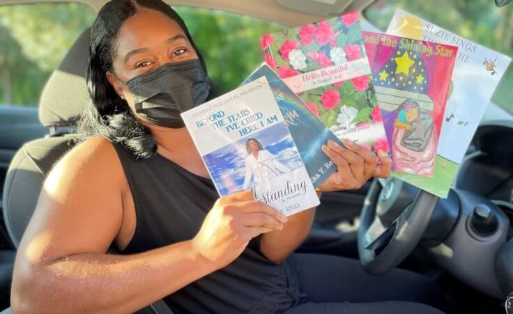 In this Wednesday, Aug. 10, 2022, photo in Princeton, N.J., Tomika Reid holds books that she’s authored. Reid, a single mother and children’s book author in the Princeton area, works as a ride-hailing service driver and tries to inspire passengers through spiritual guidance on the road as part of what she sees as a ride-hailing ministry. (AP Photo/Luis Andres Henao)