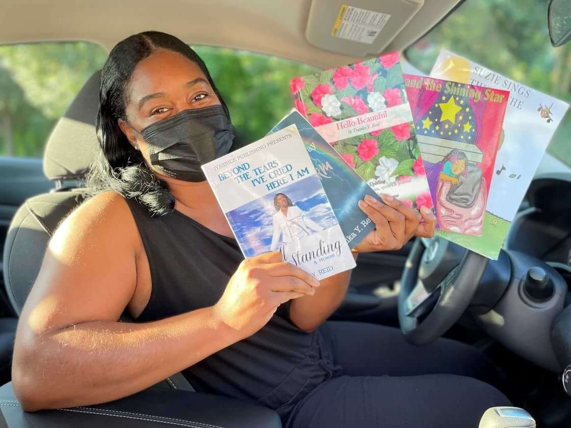 In this Wednesday, Aug. 10, 2022, photo in Princeton, N.J., Tomika Reid holds books that she’s authored. Reid, a single mother and children’s book author in the Princeton area, works as a ride-hailing service driver and tries to inspire passengers through spiritual guidance on the road as part of what she sees as a ride-hailing ministry. (AP Photo/Luis Andres Henao)
