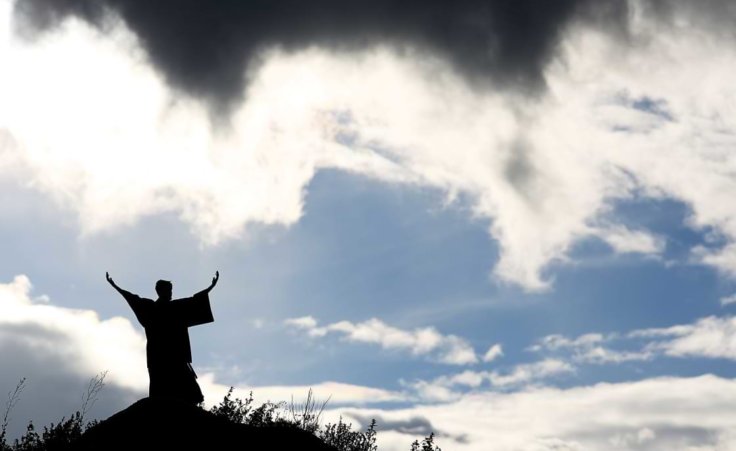 A Moses-like silhouette stands on a mountain with both arms upraised