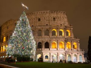 A well-lit Christmas tree stands outside of the Coliseum in Rome, Italy, at night. © By Matteo Gabrieli/stock.adobe.com